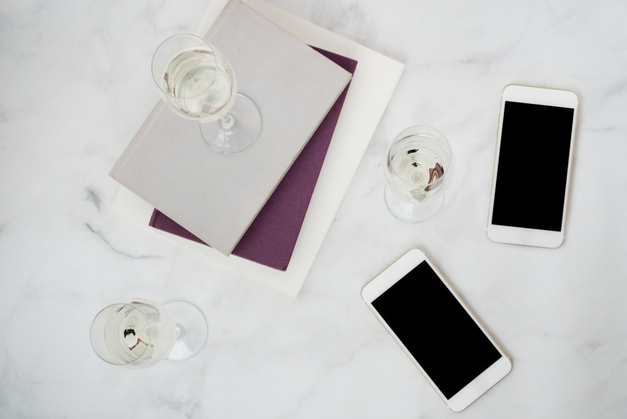Wine glass on top of books and iPhones