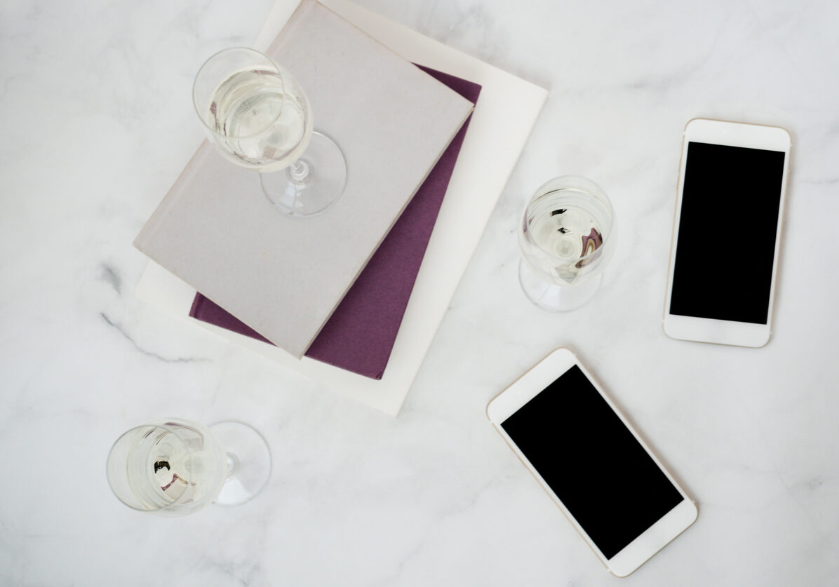 Wine glass on top of books and iPhones