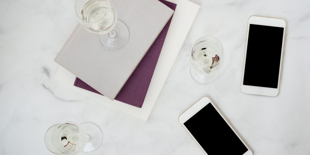 Wine glass on top of books and iPhones